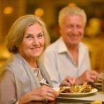 senior man and woman smiling while dining at a restaurant