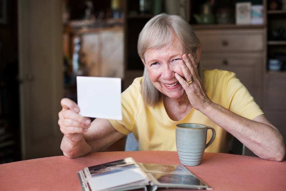 senior woman looking at photo and laughing
