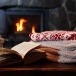 Blankets, book, lantern near fireplace