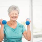 Smiling senior woman lifting small hand weights