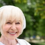 Smiling senior woman wearing headphones outside