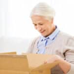 Smiling senior woman opening cardboard box