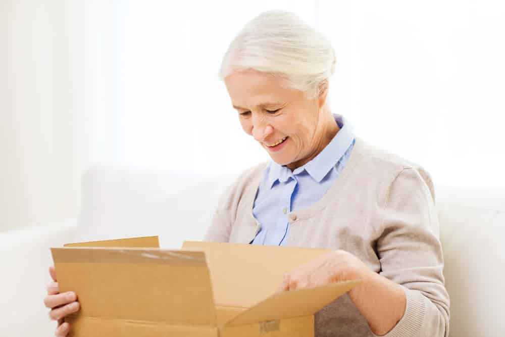 Smiling senior woman opening cardboard box