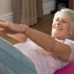 Senior woman doing crunches on yoga mat indoors