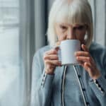 Senior woman drinking coffee near window