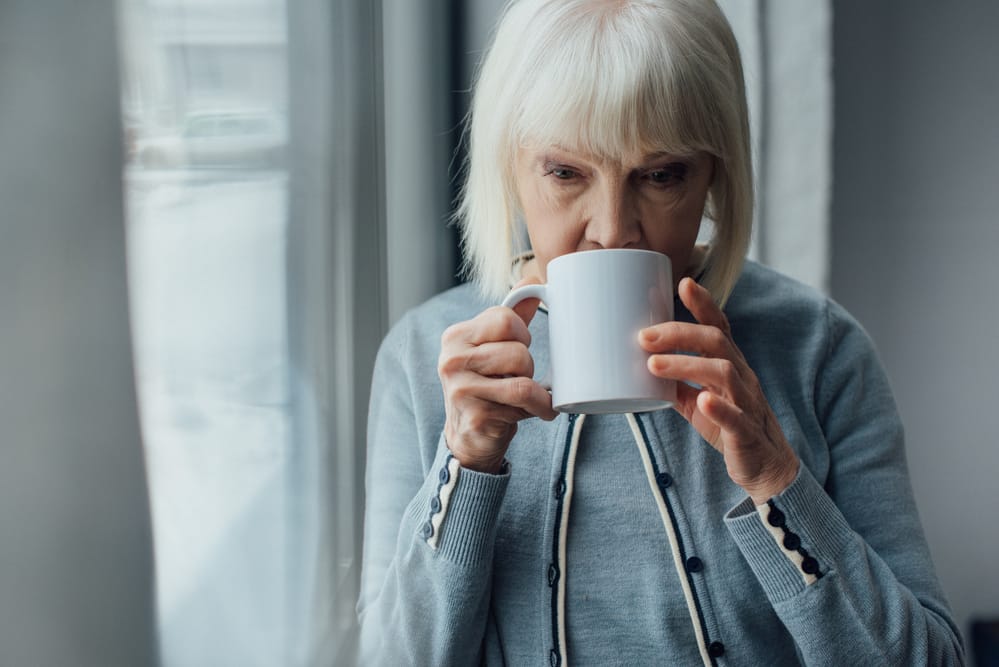Senior woman drinking coffee near window