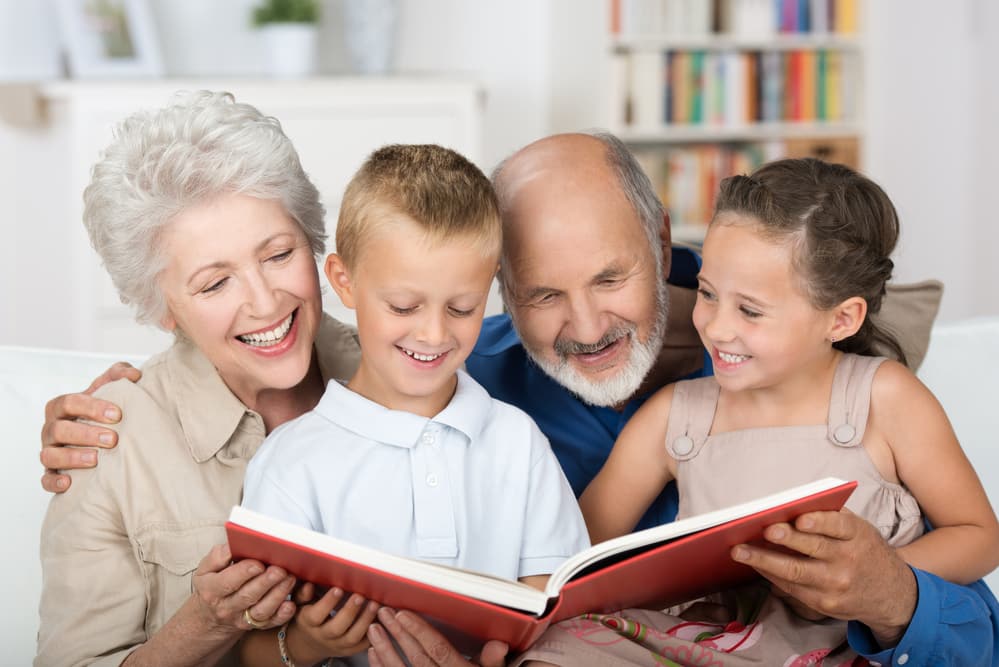 Grandparents and grandchildren smiling while looking at memory book