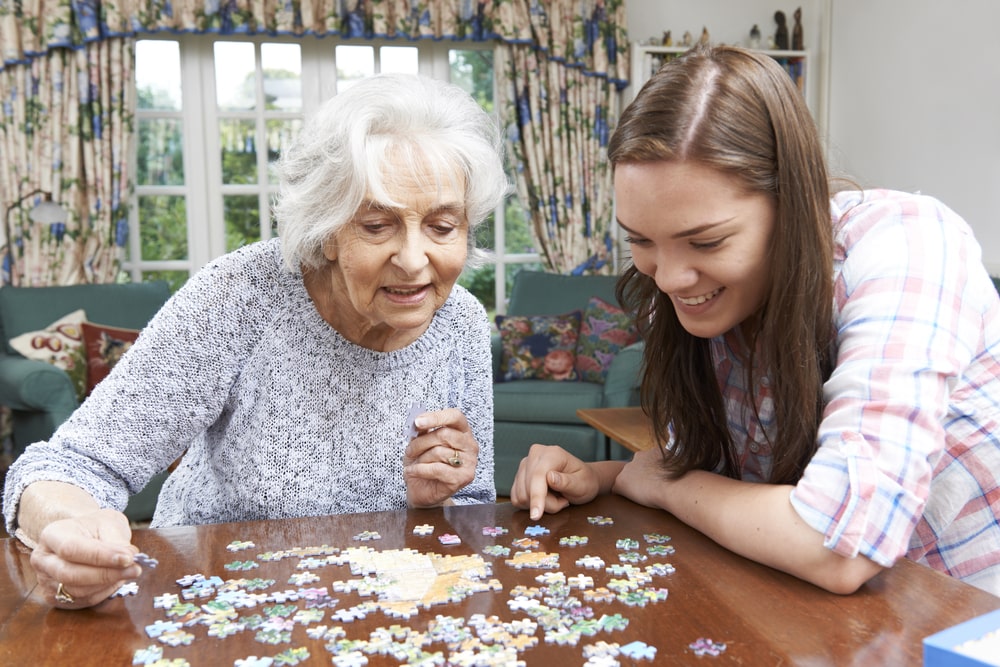 Senior woman and young woman completing puzzle