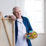 Senior man with easel and painting palette