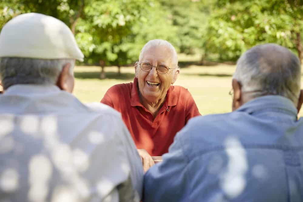 Senior man laughing with two friends outside
