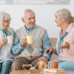 Three seniors smiling and chatting over coffee