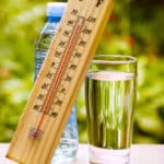 Glass of water, water bottle, wood thermometer reading over 100 F, outdoors