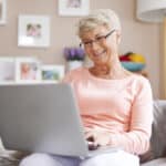 Senior woman smiling using laptop