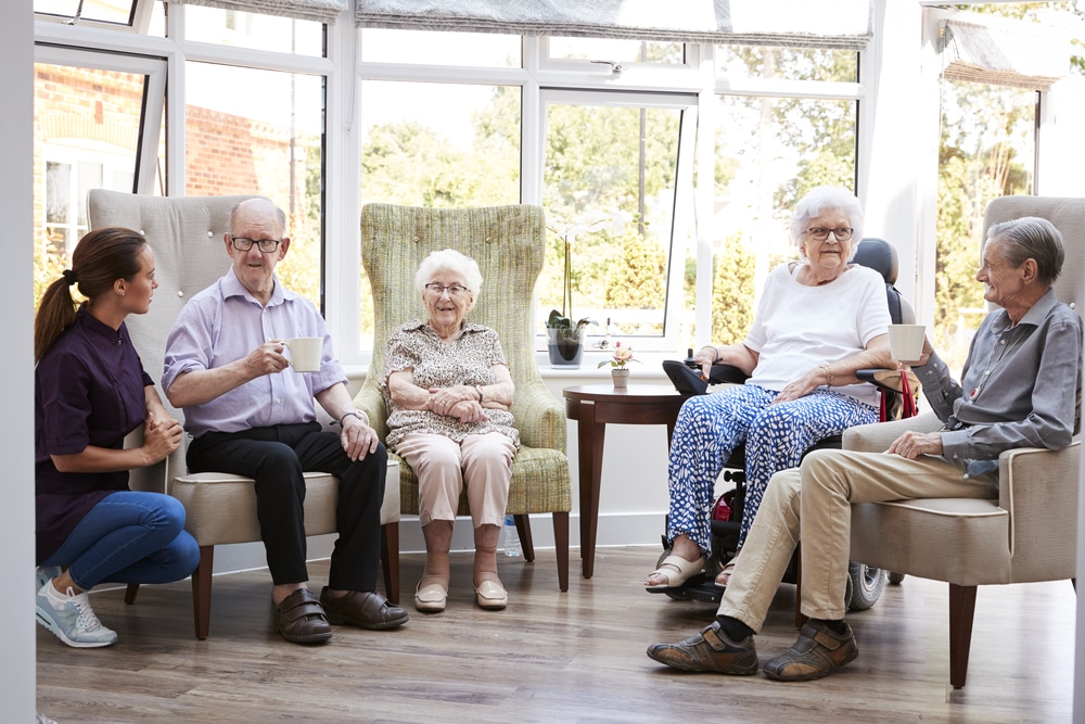 four seniors sitting and chatting, one carer talking to them