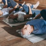 Seniors lying on yoga mats, stretching their legs