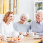 Several smiling seniors chatting and having coffee and snack