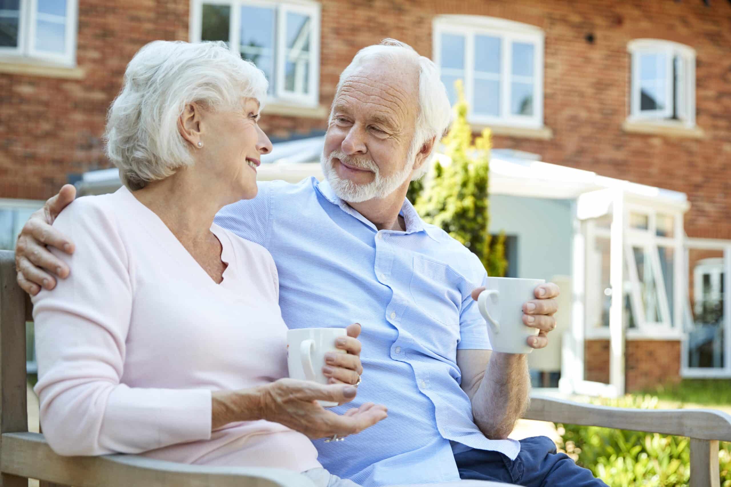 Senior couple smiling, drinking coffee outside