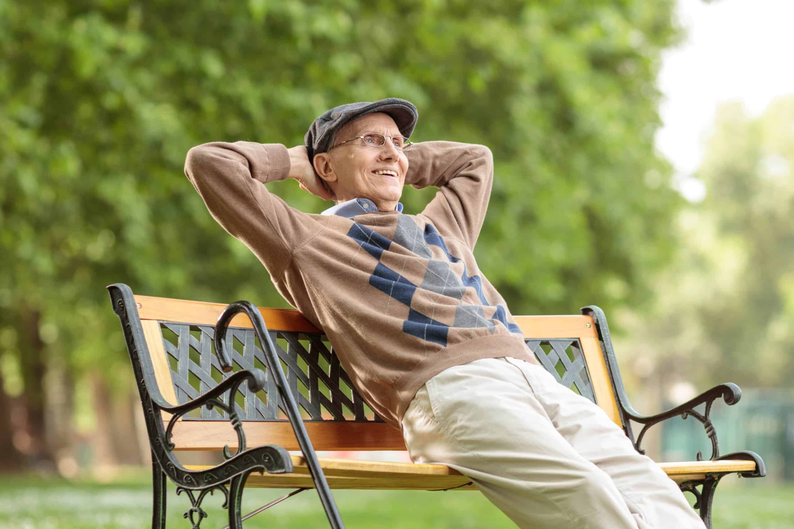 Senior man relaxing happily on park bench