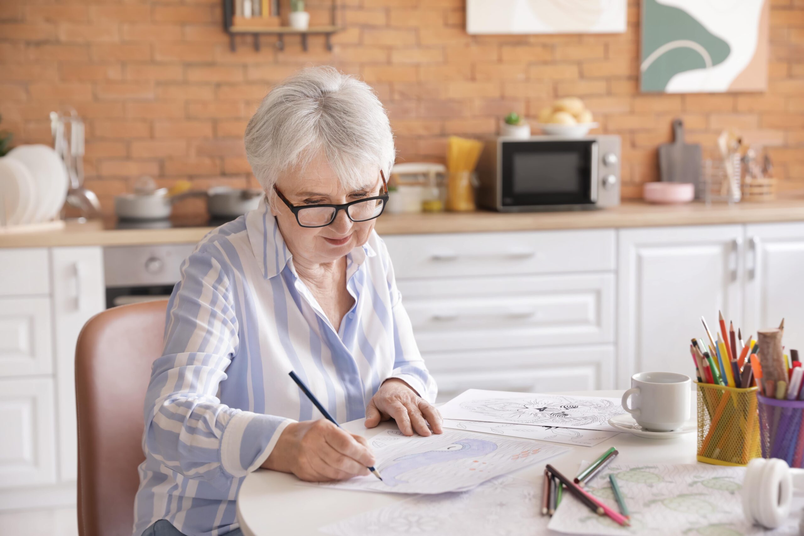 Senior woman coloring a picture at a kitchen table